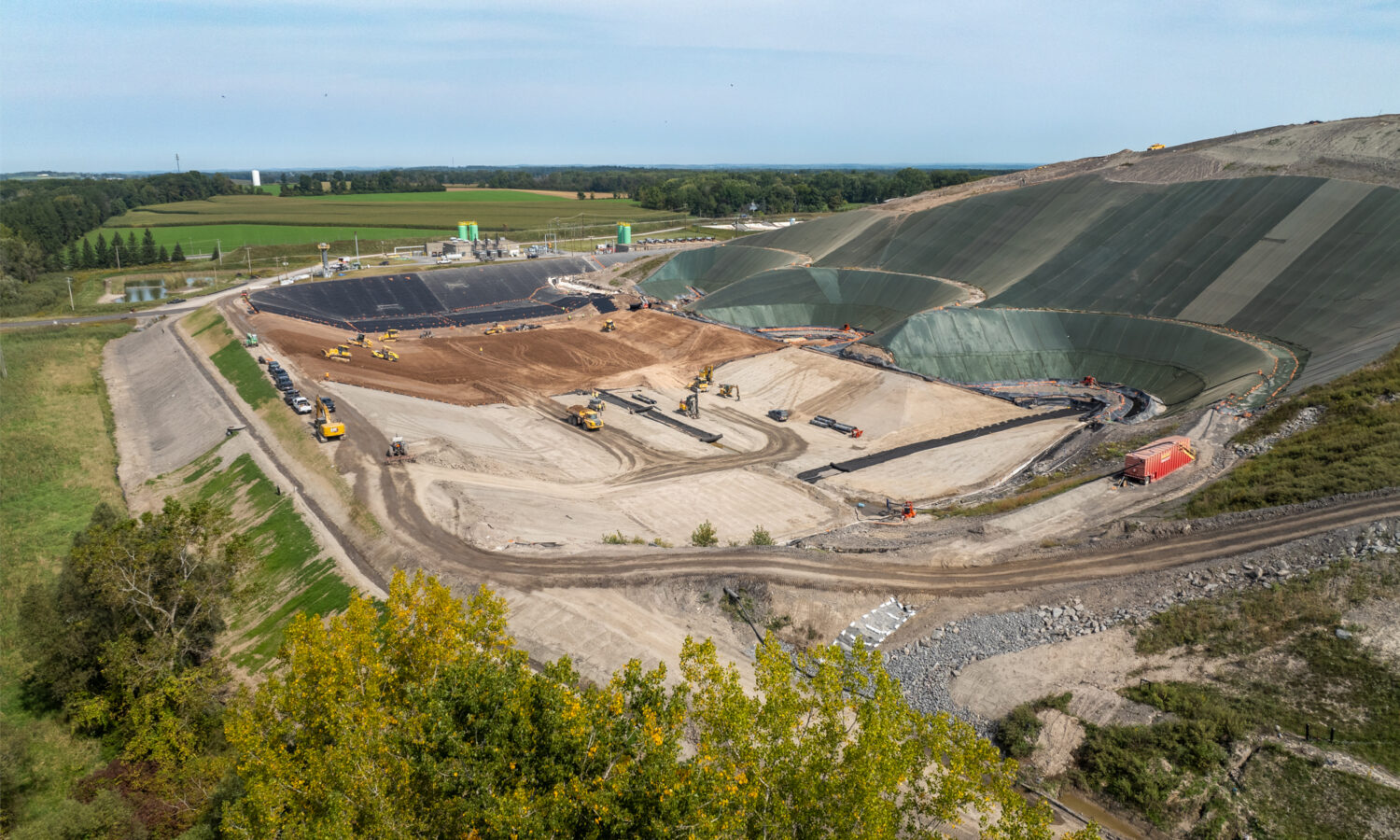Aerial view: landfill site, machinery, earthmovers, geomembrane liners.