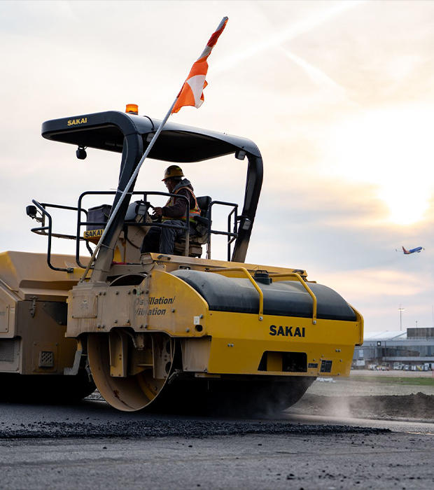 Runway construction at dusk; plane takes off at sunset